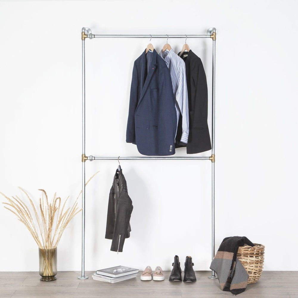 Stilrent vandrør tøjstativ med messing fittings til væg med dobbelt bøjlestang så der er plads til en hel garderobe.