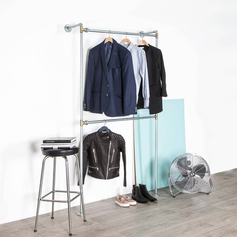 Stilrent vandrør tøjstativ med messing fittings til væg med dobbelt bøjlestang så der er plads til en hel garderobe.